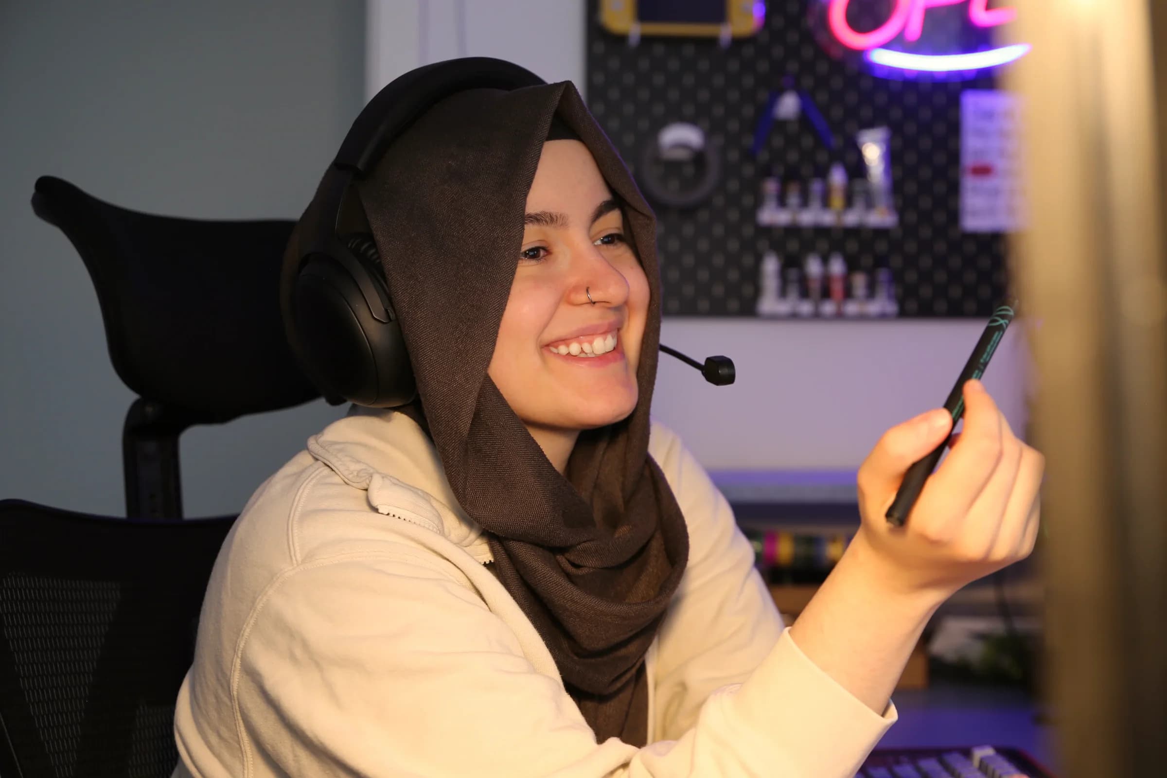 Ipek Moosheimer lächelt am Schreibtisch mit Headset und Stift in der Hand, während einer Online-Mentoring-Session